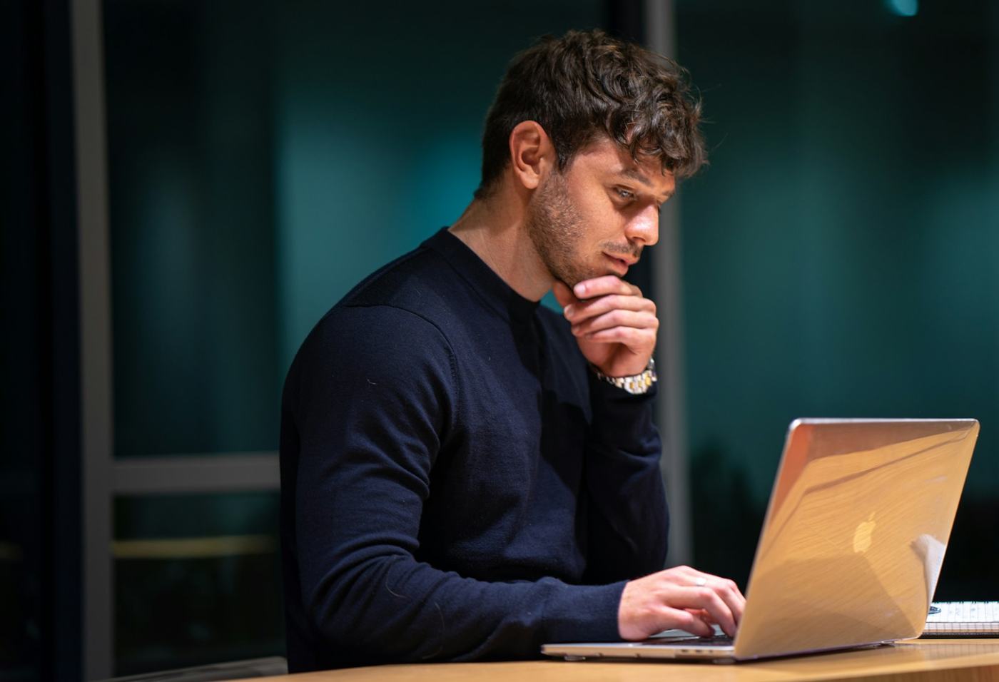 Mężczyzna pracujący przy laptopie wieczorem