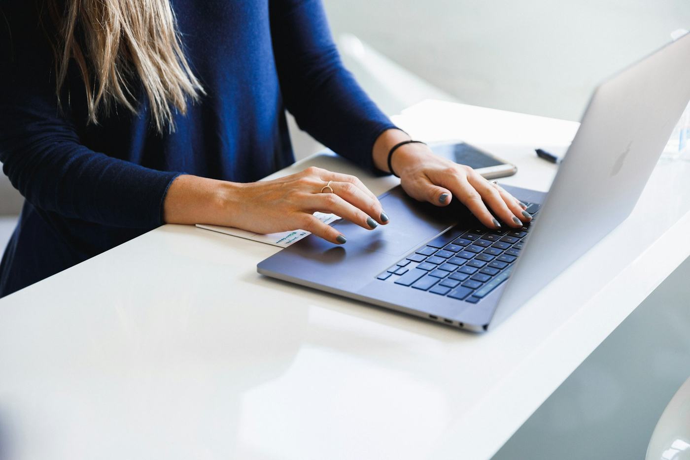 Dłonie na klawiaturze laptopa przy jasnym biurku